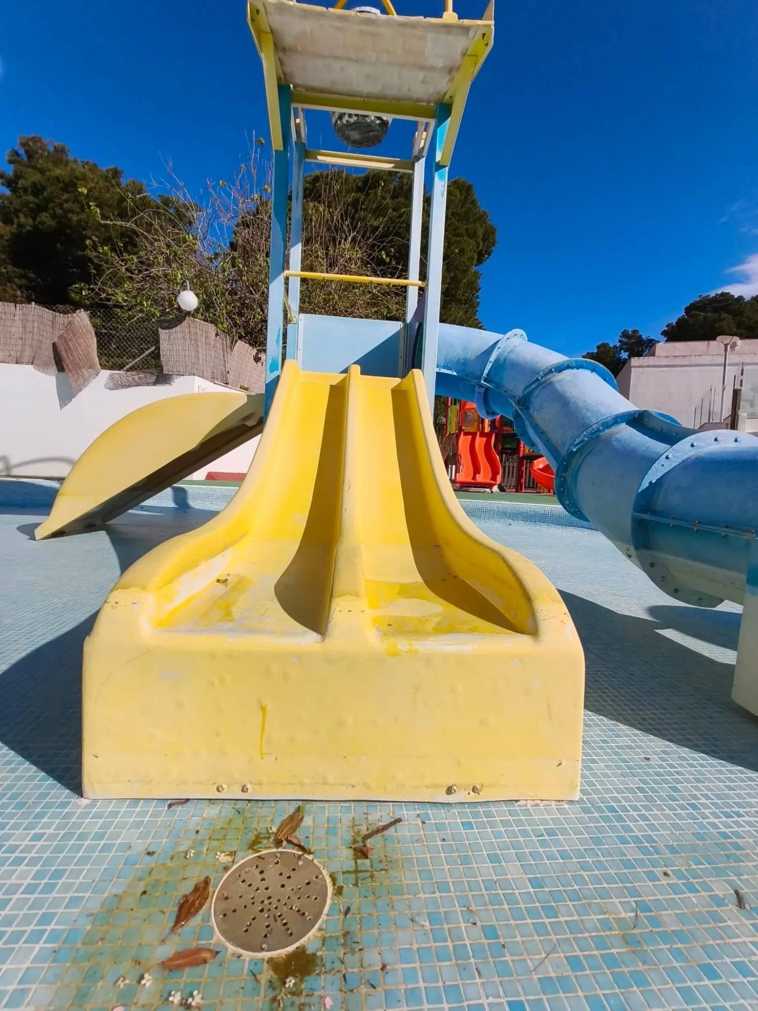 Torre de juegos acuáticos con el tobogán amarillo descolorido y desgastado antes de restaurarla