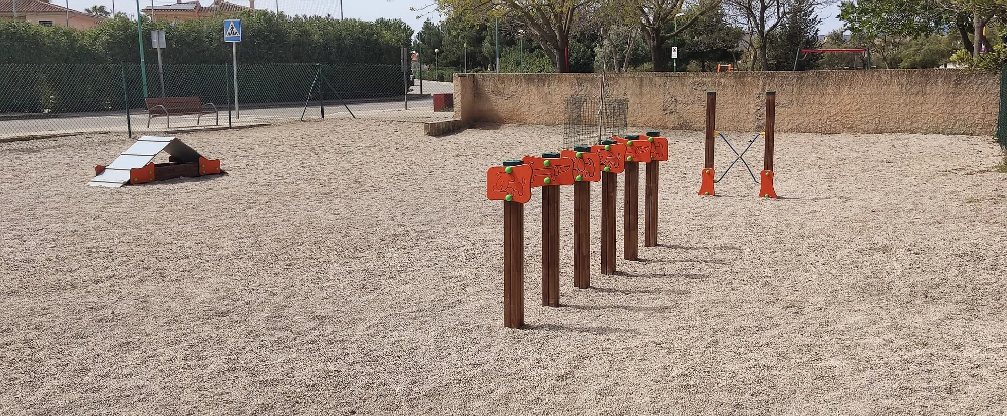 Recinto canino con slalom, empalizada y salto de altura sobre gravilla