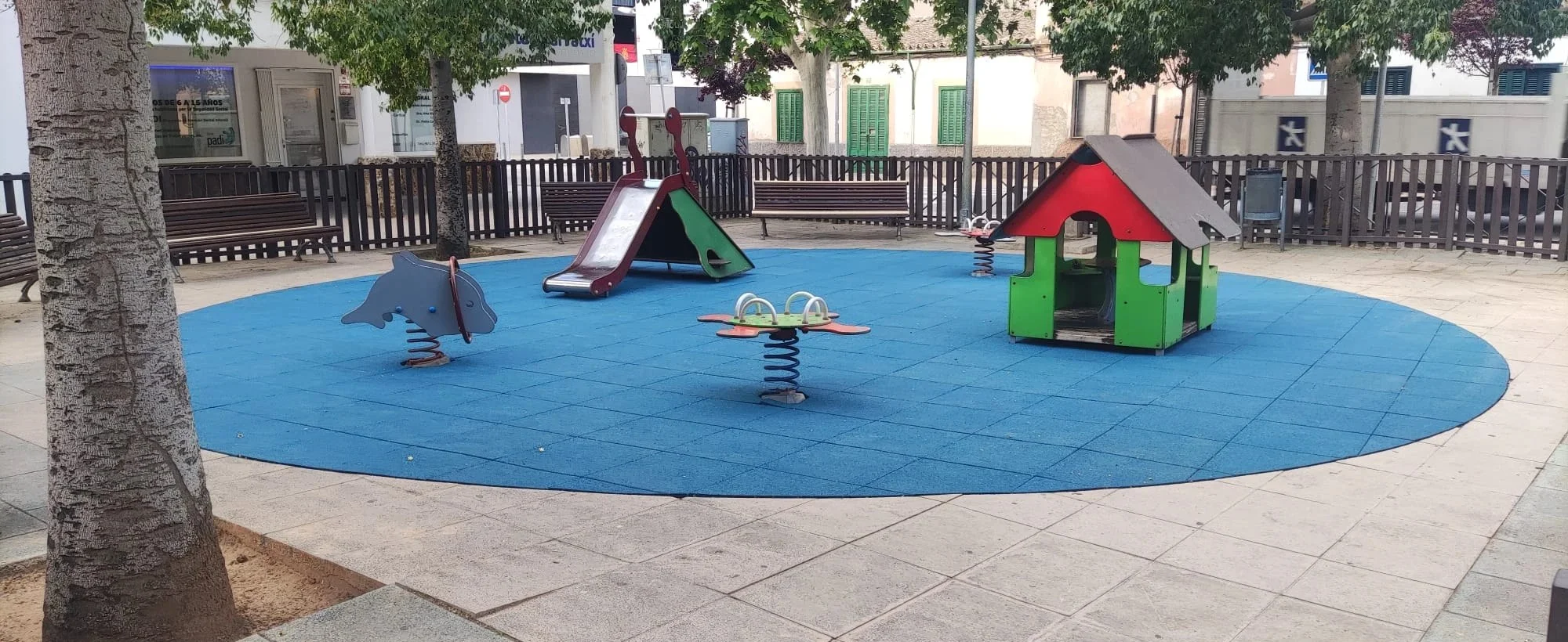 Parque infantil con el pavimento de caucho azul nuevo tras la renovación
