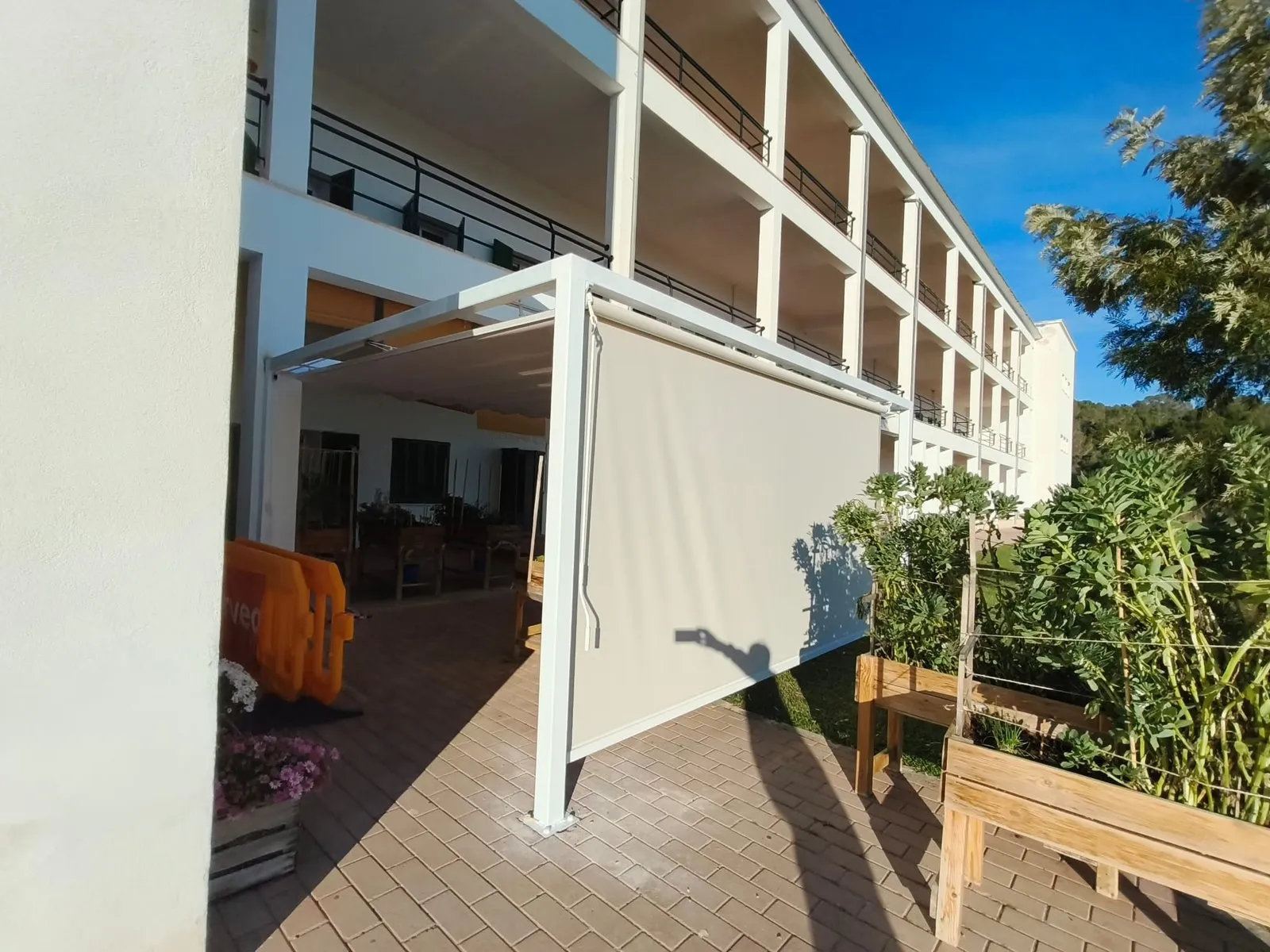 Pérgola blanca con toldo retráctil instalada en una terraza