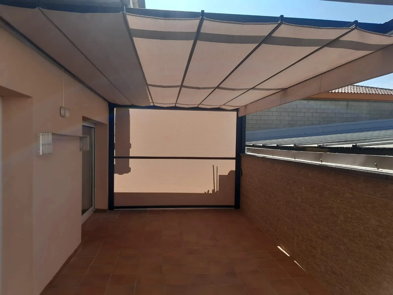 Pérgola con toldo plegable y cortina vertical cerrando una terraza