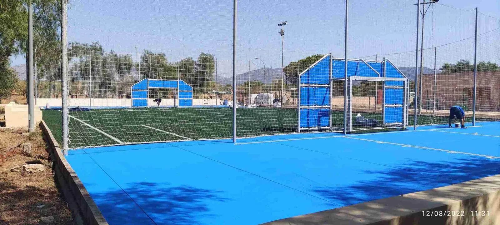 Pista deportiva azul con porterías y canasta