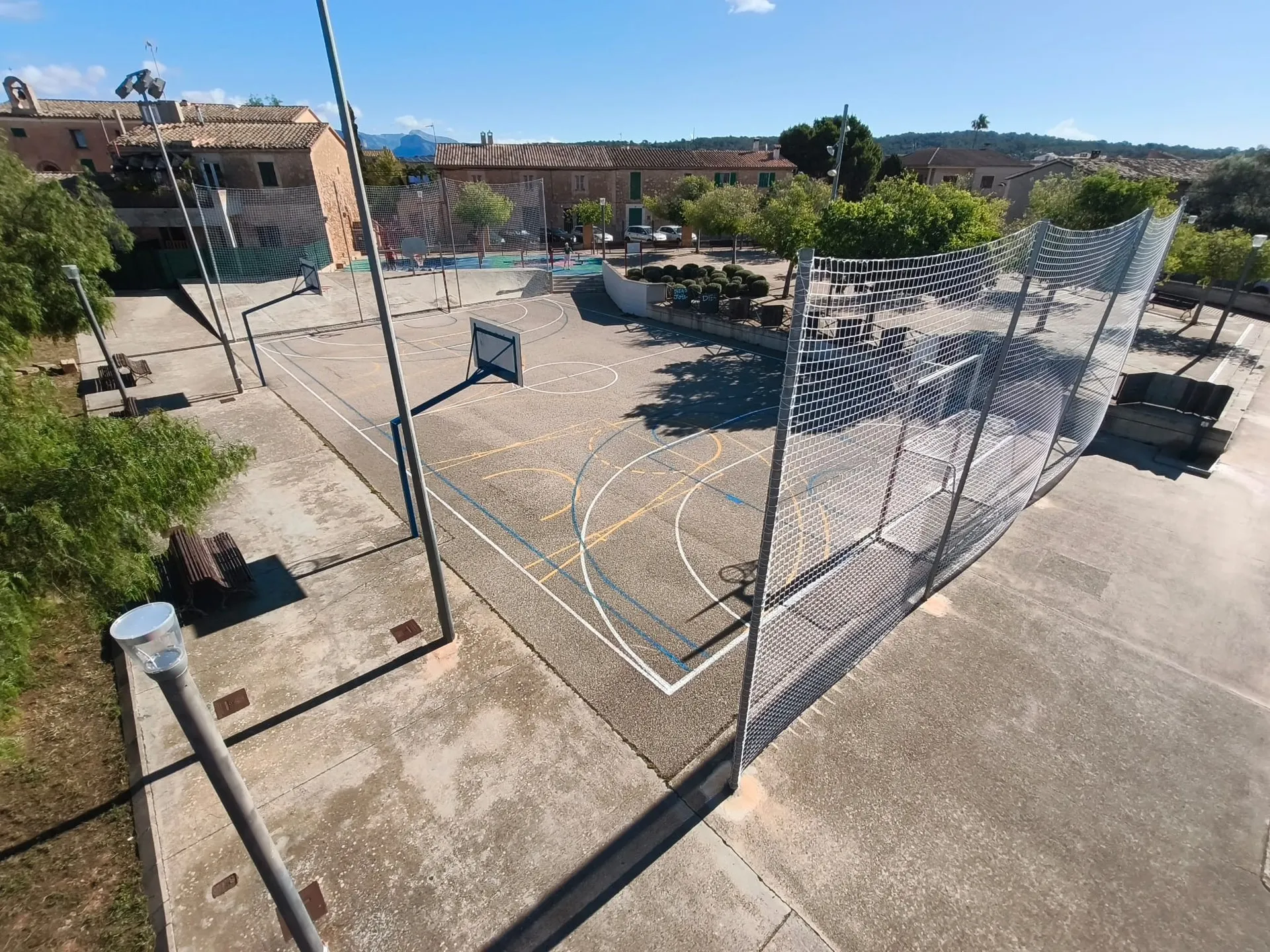 Vista elevada de una pista multideporte con red parapelotas instalada