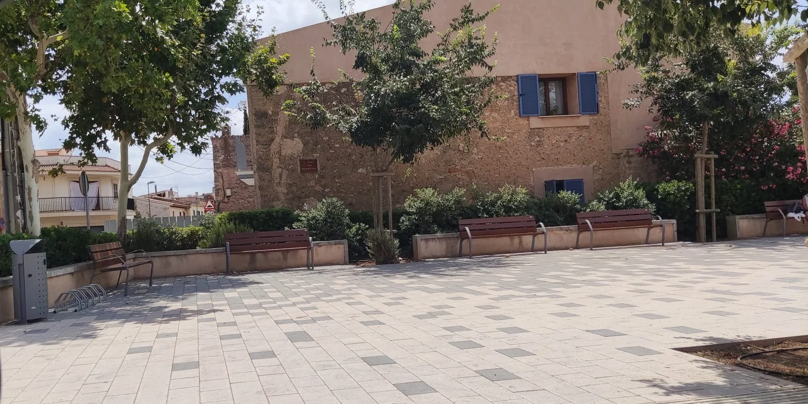 Plaza urbana con bancos de madera, jardineras, papelera y aparcabicis