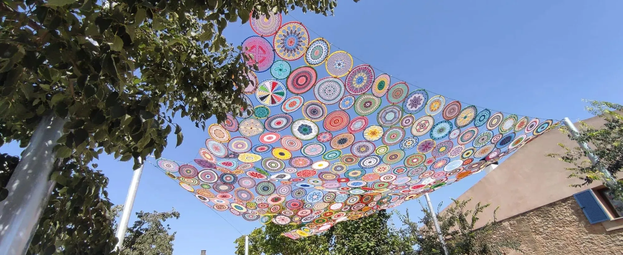 Cubierta de sombra de mandalas de ganchillo de colores tensada sobre una calle