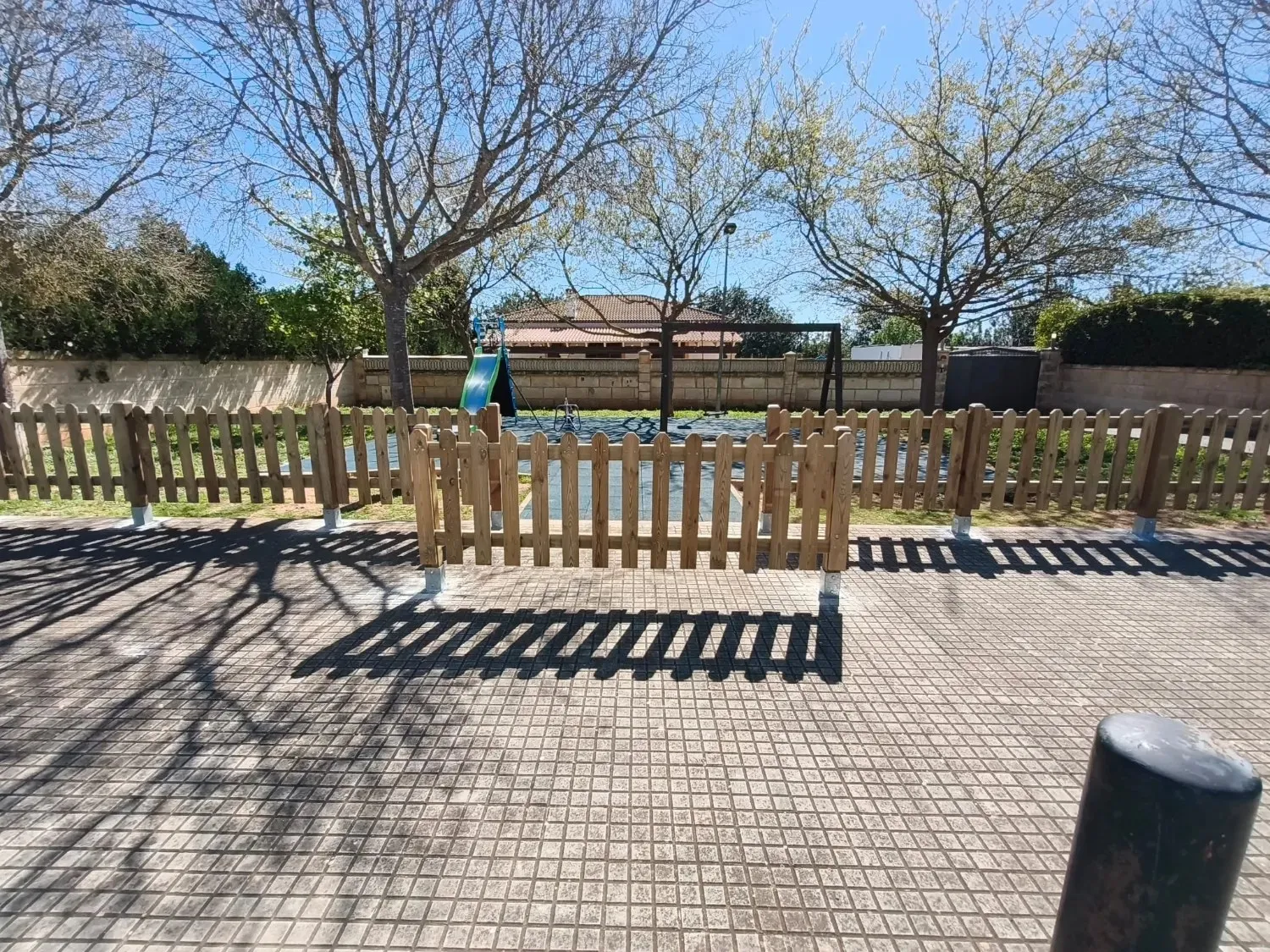 Vallado de madera tratada con puerta delimitando un parque infantil